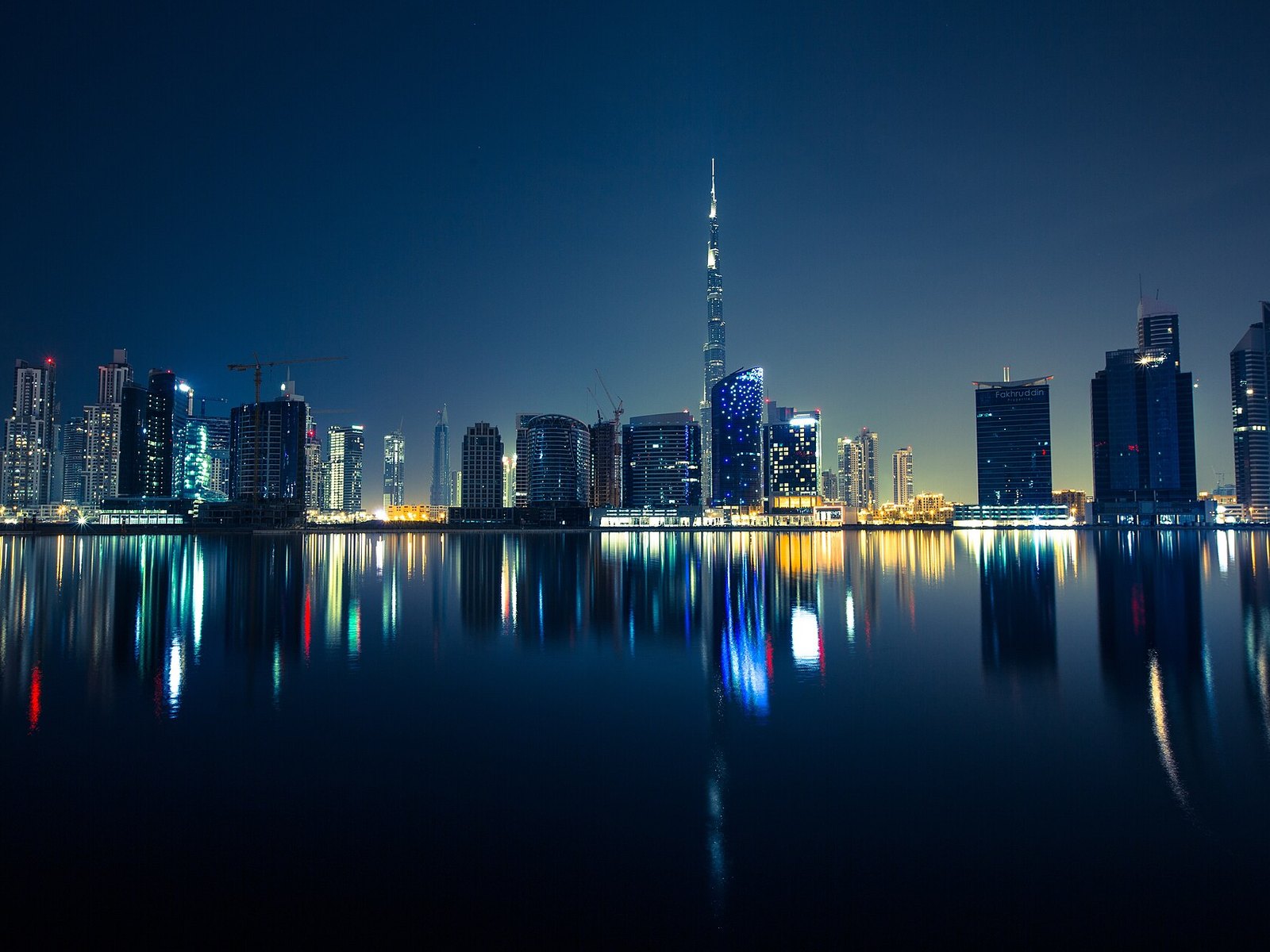 Dubai Business Bay skyline and Burj Khalifa reflected in the water at night